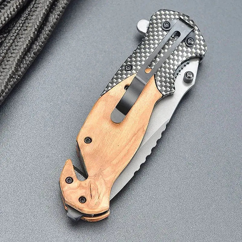 Folding knife with a partially serrated stainless steel blade, wooden and carbon fiber-patterned handle, placed against a bundle of black braided rope.